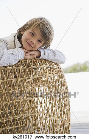 Stock Photo - Portrait of a boy leaning on a wicker chair. Fotosearch