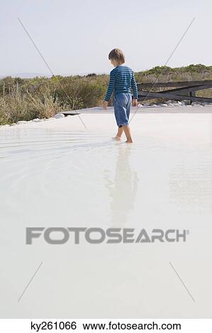 Rear view of a boy walking in an infinity pool View Large Photo Image Stock Photograph - Rear view of a boy walking in an infinity pool. Fotosearch