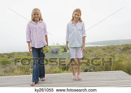 Two girls carrying a box of flowers and smiling View Large Photo Image Stock Photography - Two girls carrying a box of flowers and smiling. Fotosearch