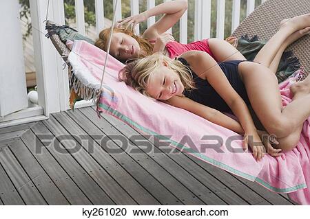 Two girls lying on a porch swing View Large Photo Image Stock Image - Two girls lying on a porch swing. Fotosearch