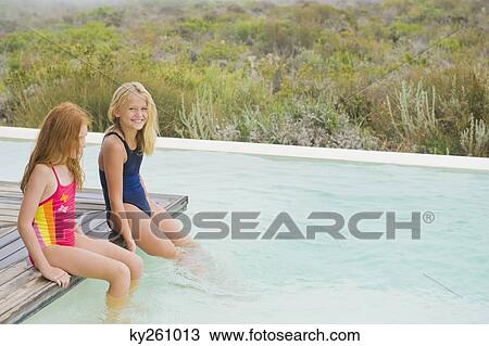 Two girls sitting on a platform at an infinity pool View Large Photo Image Stock Image - Two girls sitting on a platform at an infinity pool. Fotosearch