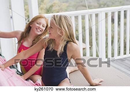 Two girls sitting on a porch swing View Large Photo Image Stock Image - Two girls sitting on a porch swing. Fotosearch