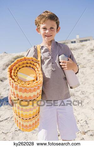 Stock Photo - Boy carrying mat on the beach. Fotosearch