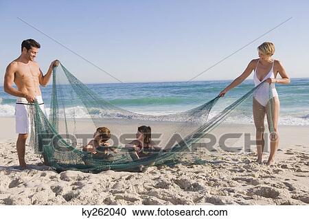 Stock Image - Family playing with a fishing net on the beach. Fotosearch