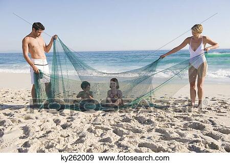 Stock Photo - Family playing with a fishing net on the beach. Fotosearch