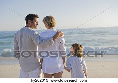 Stock Photography - Family standing on the beach. Fotosearch