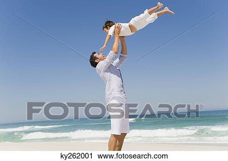 Stock Image - Man playing with his son on the beach. Fotosearch