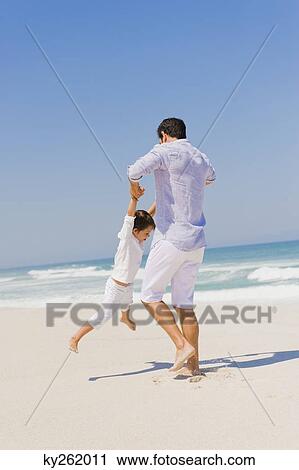 Stock Image - Man playing with his son on the beach. Fotosearch