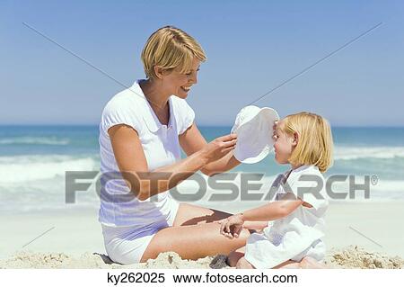 Stock Photography - Woman sitting with her daughter on the beach. Fotosearch