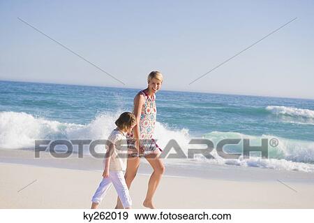 Woman walking on the beach with her daughter View Large Photo Image Stock Photo - Woman walking on the beach with her daughter. Fotosearch