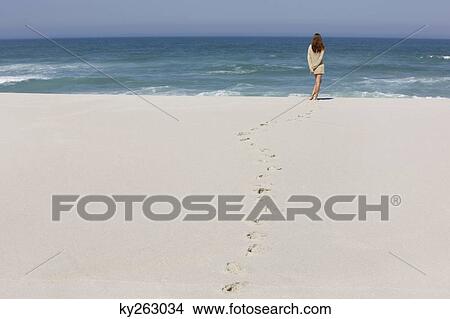 Rear view of a woman standing on the beach View Large Photo Image Picture - Rear view of a woman standing on the beach. Fotosearch
