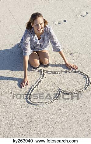 Woman drawing a heart shape on the beach View Large Photo Image Stock Image - Woman drawing a heart shape on the beach. Fotosearch