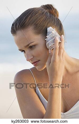 Woman listening to a conch shell View Large Photo Image Stock Image - Woman listening to a conch shell. Fotosearch