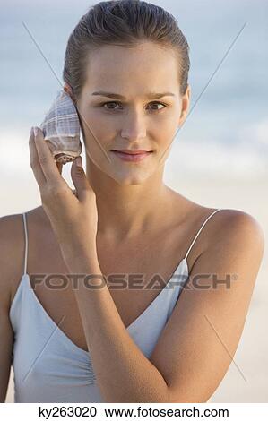 Woman listening to a conch shell View Large Photo Image Stock Image - Woman listening to a conch shell. Fotosearch