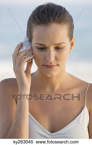 Woman listening to a conch shell View Large Photo Image Stock Photography - Woman listening to a conch shell. Fotosearch
