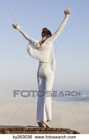 Woman standing on a boardwalk with her arms raised View Large Photo Image Stock Photograph - Woman standing on a boardwalk with her arms raised. Fotosearch