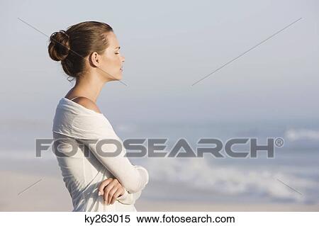 Stock Photography - Woman standing on the beach and thinking. Fotosearch