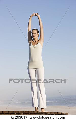 Woman stretching her arms on a boardwalk View Large Photo Image Stock Photo - Woman stretching her arms on a boardwalk. Fotosearch