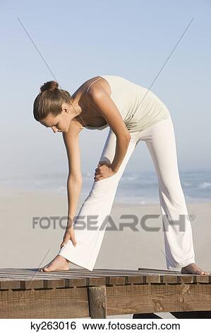 Woman stretching on a boardwalk View Large Photo Image Stock Photograph - Woman stretching on a boardwalk. Fotosearch
