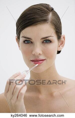 Fashion model applying lip gloss on her lips View Large Photo Image Stock Photograph - Fashion model applying lip gloss on her lips. Fotosearch