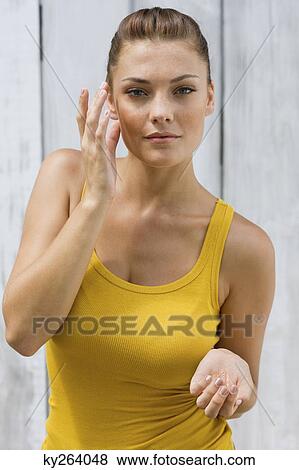 Woman applying moisturizer on her face View Large Photo Image Stock Photo - Woman applying moisturizer on her face. Fotosearch
