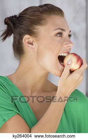 Woman eating an apple and smiling View Large Photo Image Picture - Woman eating an apple and smiling. Fotosearch