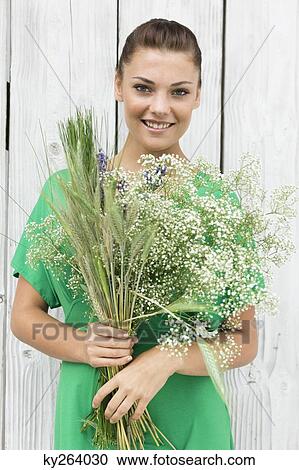 Woman holding a bouquet of flowers and smiling View Large Photo Image Stock Image - Woman holding a bouquet of flowers and smiling. Fotosearch
