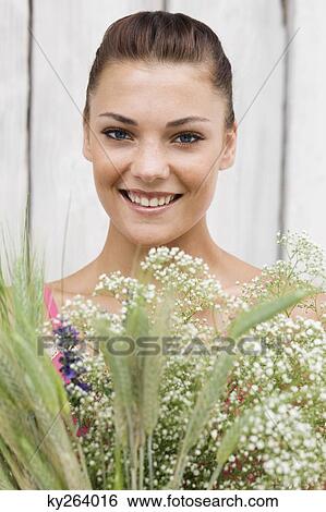 Woman holding a bouquet of flowers and smiling View Large Photo Image Stock Photograph - Woman holding a bouquet of flowers and smiling. Fotosearch