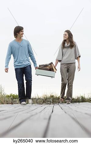 Couple carrying firewood on a boardwalk View Large Photo Image Stock Image - Couple carrying firewood on a boardwalk. Fotosearch