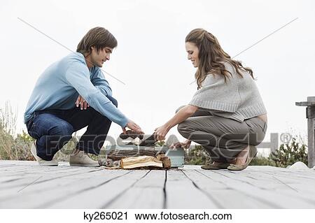 Couple holding firewood on a boardwalk View Large Photo Image Stock Image - Couple holding firewood on a boardwalk. Fotosearch