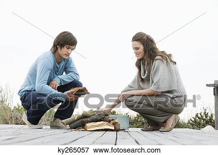 Stock Photo - Couple holding firewood on a boardwalk. Fotosearch