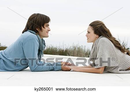 Stock Image - Couple holding hands of each other and smiling. Fotosearch