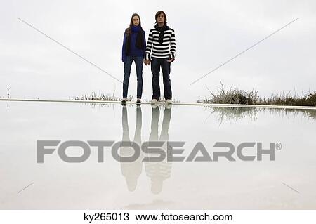 Couple standing at the poolside View Large Photo Image Stock Image - Couple standing at the poolside. Fotosearch