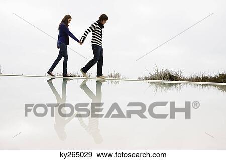 Couple walking on the ledge of a swimming pool View Large Photo Image Stock Photo - Couple walking on the ledge of a swimming pool. Fotosearch