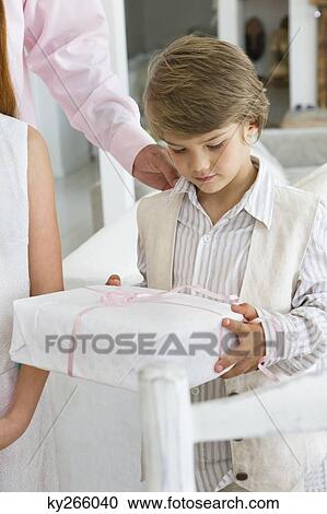 Boy holding a gift standing beside a girl View Large Photo Image Stock Image - Boy holding a gift standing beside a girl. Fotosearch