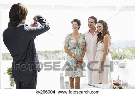 Groom taking a picture of bride with her parents at a wedding party View Large Photo Image Picture - Groom taking a picture of bride with her parents at a wedding party. Fotosearch