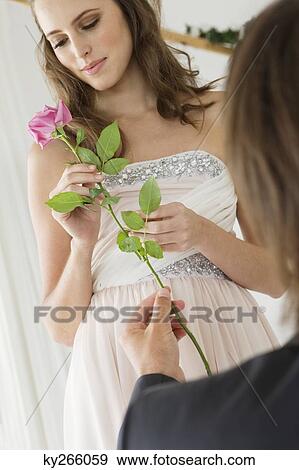 Stock Photo - Man giving a flower to a woman in the bedroom. Fotosearch