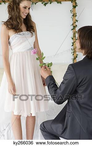 Stock Photograph - Man giving a flower to a woman in the bedroom. Fotosearch