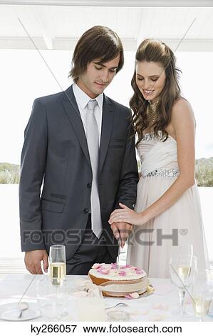 Newlywed couple cutting a wedding cake View Large Photo Image Stock Photo - Newlywed couple cutting a wedding cake. Fotosearch