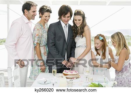 Stock Image - Newlywed couple with guests in a wedding party. Fotosearch