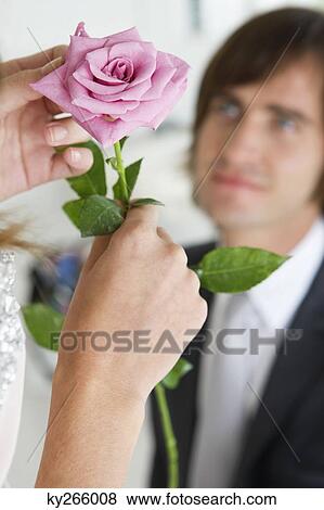 Woman holding a flower in front of a man View Large Photo Image Stock Photo - Woman holding a flower in front of a man. Fotosearch