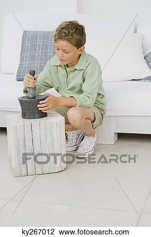 Stock Image - Boy using mortar and pestle. Fotosearch