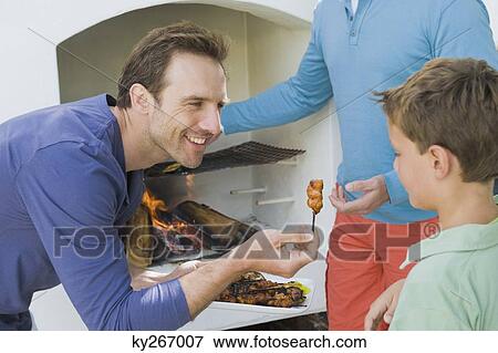 Stock Photo - Close-up of a man giving roasted kebab to his son. Fotosearch