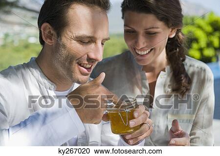 Man holding a jar of marmalade with a woman smiling beside him View Large Photo Image Stock Image - Man holding a jar of marmalade with a woman smiling beside him. Fotosearch