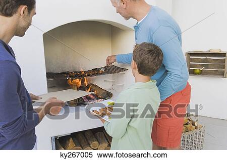 Two Men With A Boy Cooking Kebab At Fireplace Stock Photography