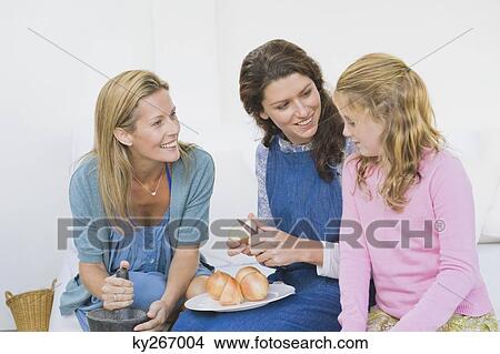 Two women preparing food with a girl at home View Large Photo Image Picture - Two women preparing food with a girl at home. Fotosearch