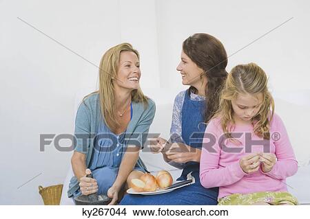 Two women preparing food with a girl at home View Large Photo Image Picture - Two women preparing food with a girl at home. Fotosearch