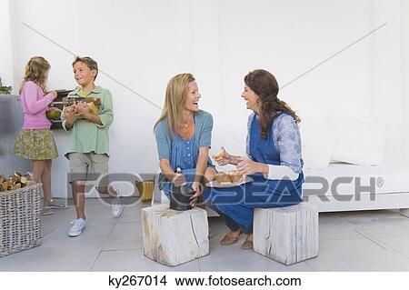 Two women preparing food with their children View Large Photo Image Picture - Two women preparing food with their children. Fotosearch