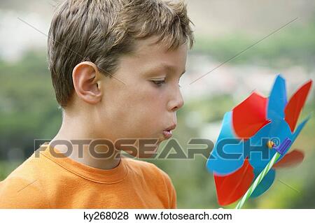 Stock Photo - Boy blowing on pinwheel. Fotosearch
