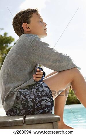 Picture - Boy day dreaming near a swimming pool. Fotosearch